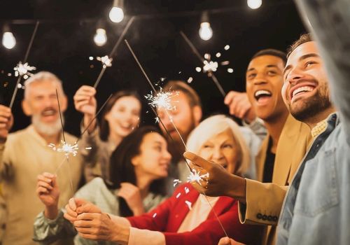 A diverse group of friends celebrating with sparklers at a night party, smiling and cheering as they shine festive lights together.