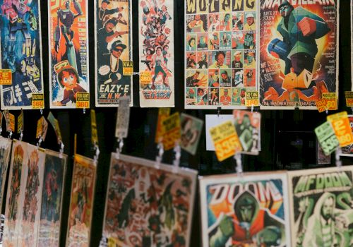 A display of vintage comic book covers and pages hanging for sale, colorful artwork with superhero and character panels, tags attached.